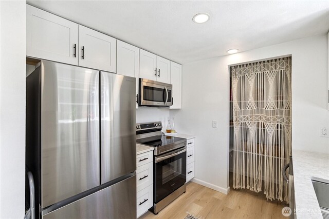 2426 Haines St, Port Townsend, WA 98368 - kitchen featuring appliances with stainless steel finishes, light countertops, light wood-style floors, white cabinetry, and recessed lighting
