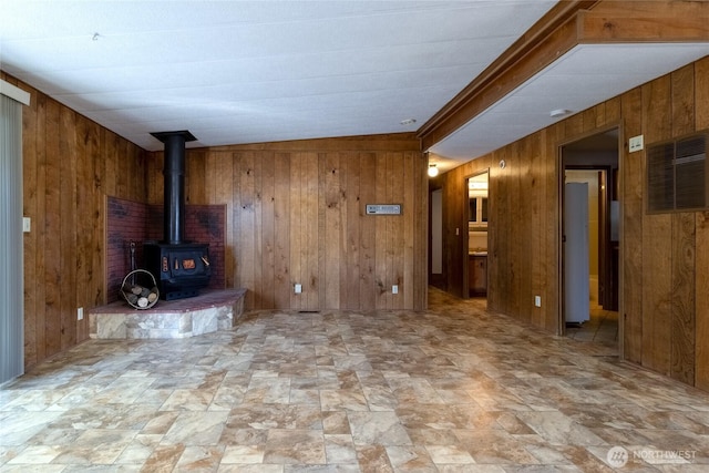 66 Onyx St, Walla Walla, WA 99362 - unfurnished living room with wooden walls, stone finish floors, and a wood stove