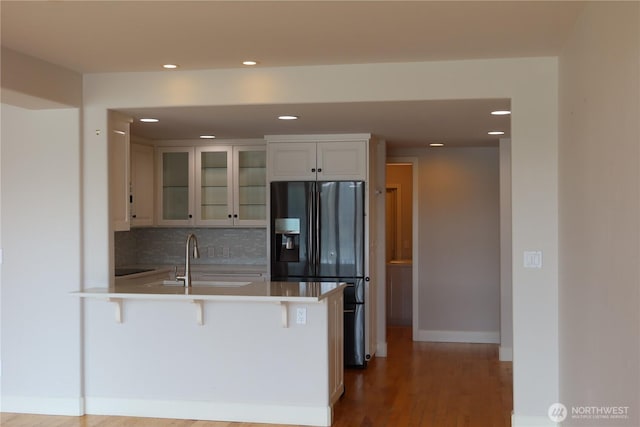 181 N Bay Ln Unit 2, Port Ludlow, WA 98165 - kitchen featuring black refrigerator with ice dispenser, a peninsula, recessed lighting, a kitchen breakfast bar, and glass insert cabinets