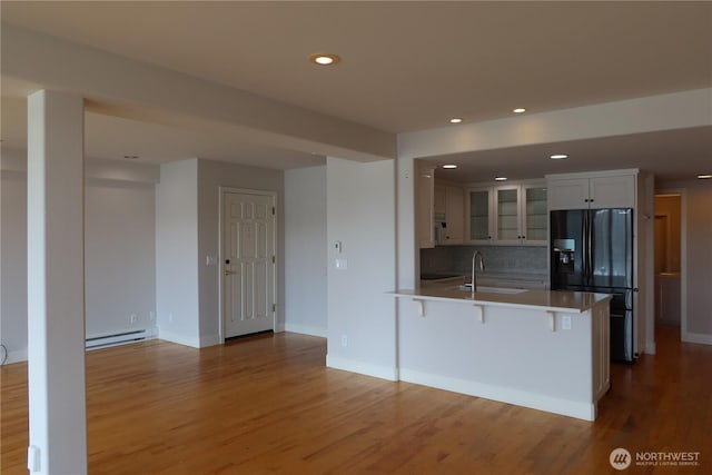 181 N Bay Ln Unit 2, Port Ludlow, WA 98165 - kitchen with black refrigerator with ice dispenser, a peninsula, glass insert cabinets, wood finished floors, and baseboard heating