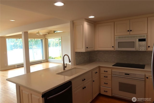 181 N Bay Ln Unit 2, Port Ludlow, WA 98165 - kitchen with black appliances, white cabinetry, light countertops, a baseboard heating unit, and tasteful backsplash