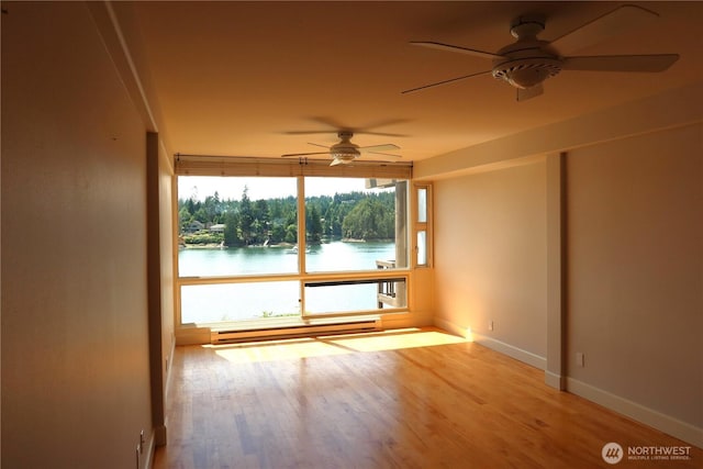 181 N Bay Ln Unit 2, Port Ludlow, WA 98165 - spare room with a ceiling fan, baseboard heating, wood finished floors, and a water view