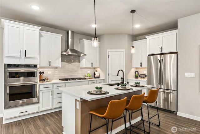 32324 135th Pl SE Unit 211, Sultan, WA 98294 - kitchen featuring appliances with stainless steel finishes, wall chimney exhaust hood, dark wood-type flooring, an island with sink, and backsplash