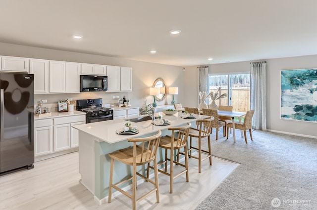 32336 135th Pl SE Unit 213, Sultan, WA 98294 - kitchen with black appliances, a kitchen island with sink, white cabinets, a breakfast bar area, and recessed lighting