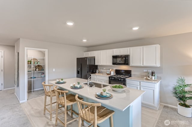 32336 135th Pl SE Unit 213, Sultan, WA 98294 - kitchen with black appliances, a breakfast bar area, white cabinets, light countertops, and an island with sink