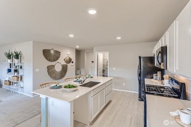 32336 135th Pl SE Unit 213, Sultan, WA 98294 - kitchen with black microwave, stainless steel gas stove, a kitchen island with sink, white cabinets, and recessed lighting