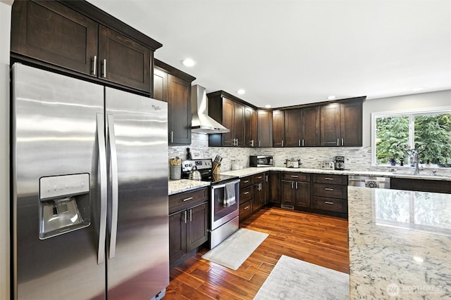 7212 188th Ave E, Bonney Lake, WA 98391 - kitchen featuring appliances with stainless steel finishes, wall chimney range hood, dark brown cabinetry, dark wood finished floors, and tasteful backsplash