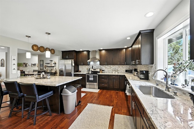7212 188th Ave E, Bonney Lake, WA 98391 - kitchen with stainless steel appliances, wall chimney range hood, dark brown cabinetry, light stone countertops, and decorative backsplash