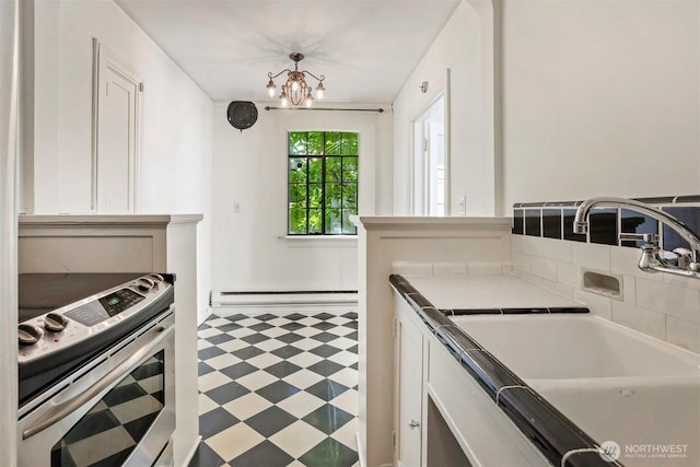 3121 Franklin Ave E Unit 24, Seattle, WA 98102 - kitchen with stainless steel electric range oven, a baseboard radiator, tile patterned floors, a chandelier, and white cabinetry