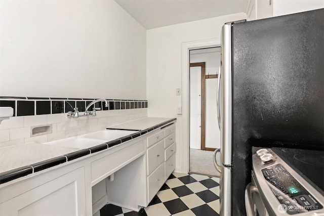3121 Franklin Ave E Unit 24, Seattle, WA 98102 - kitchen with stainless steel appliances, light floors, white cabinetry, and tasteful backsplash
