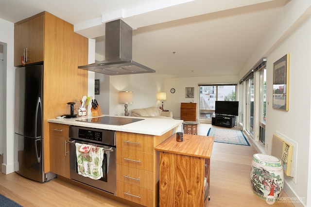 500 5th Ave W Unit 505, Seattle, WA 98119 - kitchen with stainless steel oven, wall chimney exhaust hood, freestanding refrigerator, light wood finished floors, and a peninsula