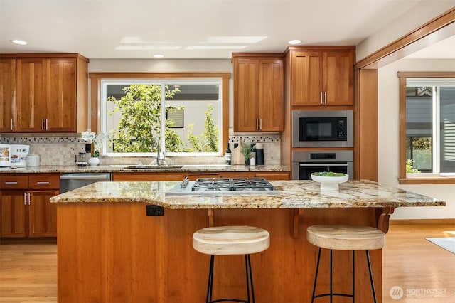 11226 NE 67th St, Kirkland, WA 98033 - kitchen with appliances with stainless steel finishes, light wood-type flooring, backsplash, a kitchen bar, and recessed lighting