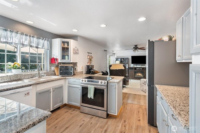 103 Nikula Rd W, Winlock, WA 98596 - kitchen featuring appliances with stainless steel finishes, a ceiling fan, light wood finished floors, recessed lighting, and a warm lit fireplace