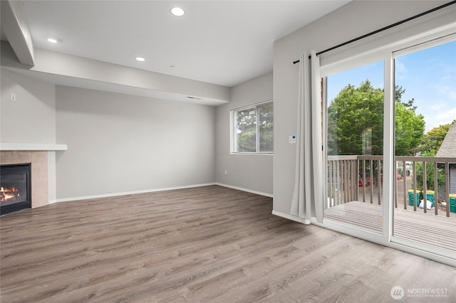 8077 165th Ln NE, Redmond, WA 98052 - unfurnished living room with wood finished floors, a tiled fireplace, and recessed lighting