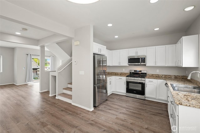 8077 165th Ln NE, Redmond, WA 98052 - kitchen featuring appliances with stainless steel finishes, recessed lighting, white cabinetry, wood finished floors, and light stone countertops