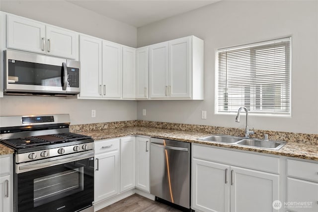 8077 165th Ln NE, Redmond, WA 98052 - kitchen with appliances with stainless steel finishes, white cabinetry, light wood-style flooring, and light stone counters