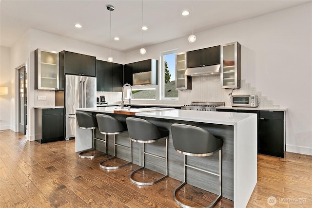 4113 Palatine Ave N, Seattle, WA 98103 - kitchen featuring high end fridge, light countertops, a center island with sink, light wood finished floors, and a breakfast bar
