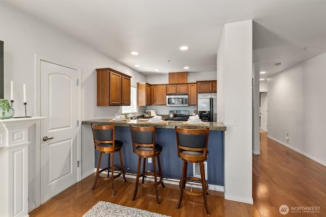 3112 SW Avalon Way Unit 102, Seattle, WA 98126 - kitchen featuring appliances with stainless steel finishes, wood finished floors, brown cabinets, a peninsula, and recessed lighting