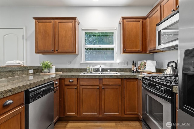 3112 SW Avalon Way Unit 102, Seattle, WA 98126 - kitchen with stainless steel appliances, dark countertops, brown cabinetry, and light wood finished floors