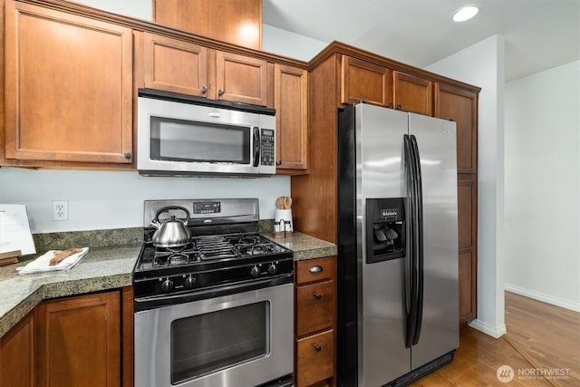 3112 SW Avalon Way Unit 102, Seattle, WA 98126 - kitchen with appliances with stainless steel finishes, brown cabinets, wood finished floors, recessed lighting, and dark stone countertops