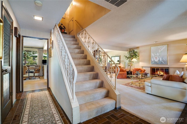3500 SW 325th St, Federal Way, WA 98023 - stairway featuring a textured ceiling, a glass covered fireplace, and brick patterned floors