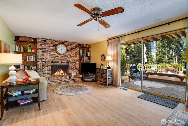 3500 SW 325th St, Federal Way, WA 98023 - living room featuring wood finished floors, ceiling fan, a textured ceiling, and a brick fireplace