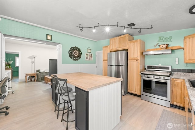 6070 Saxon Rd, Acme, WA 98220 - kitchen featuring appliances with stainless steel finishes, a breakfast bar area, light wood-type flooring, a kitchen island, and light brown cabinets