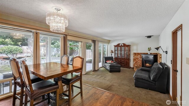 16621 148th Ave SE, Renton, WA 98058 - dining area featuring a textured ceiling, a chandelier, wood finished floors, a glass covered fireplace, and carpet floors