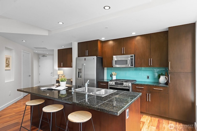 910 Lenora St Unit S403, Seattle, WA 98121 - kitchen featuring stainless steel appliances, a breakfast bar area, a center island with sink, light wood-style floors, and tile countertops