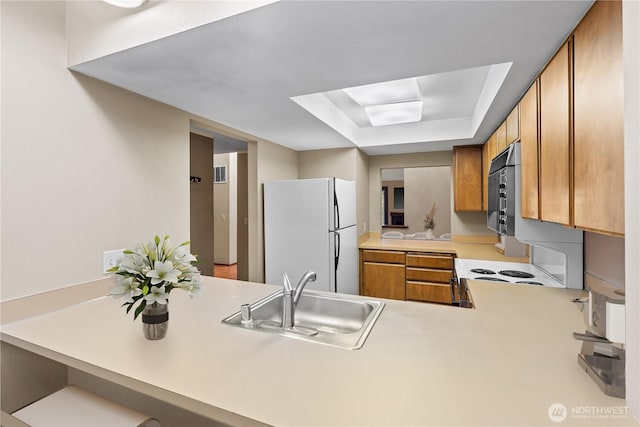 2514 174th Ave NE, Redmond, WA 98052 - kitchen featuring white appliances, a raised ceiling, light countertops, brown cabinets, and a peninsula