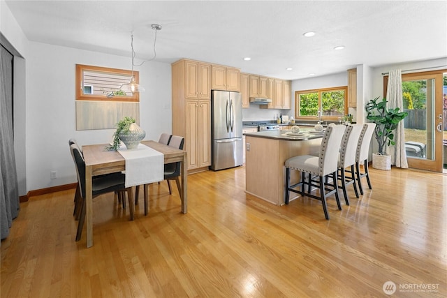 23303 13th Pl W, Bothell, WA 98021 - kitchen featuring freestanding refrigerator, under cabinet range hood, a kitchen breakfast bar, light brown cabinets, and a center island