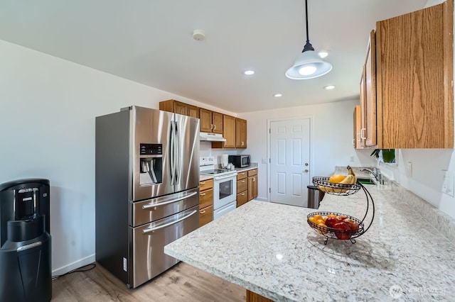 721 S 304th St, Federal Way, WA 98003 - kitchen featuring appliances with stainless steel finishes, under cabinet range hood, brown cabinetry, light wood-type flooring, and a peninsula