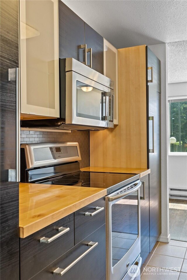 24814 SE 145th Ln, Kent, WA 98042 - kitchen with appliances with stainless steel finishes, a textured ceiling, decorative backsplash, baseboard heating, and light tile patterned floors