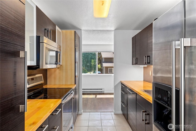 24814 SE 145th Ln, Kent, WA 98042 - kitchen with appliances with stainless steel finishes, a baseboard heating unit, butcher block countertops, a textured ceiling, and light tile patterned floors