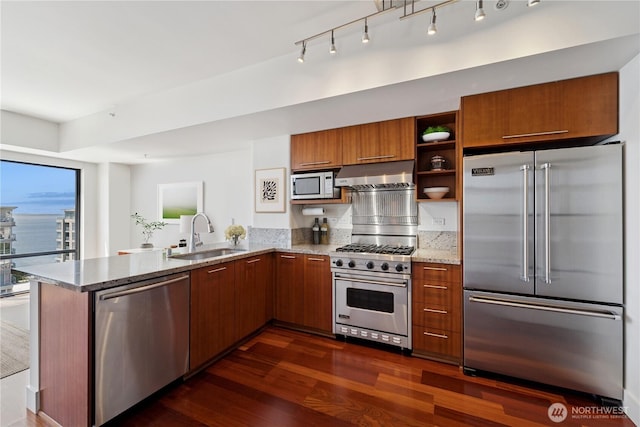 2911 2nd Ave Unit 1117, Seattle, WA 98121 - kitchen with premium appliances, range hood, brown cabinetry, a peninsula, and dark wood-style flooring