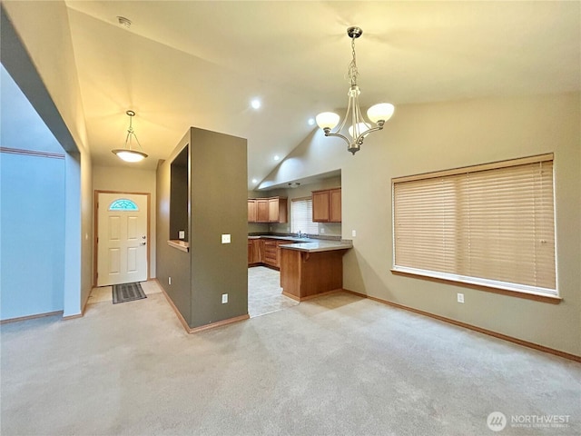 4544 Durham St SE, Lacey, WA 98503 - kitchen featuring brown cabinets, a chandelier, lofted ceiling, a peninsula, and light colored carpet