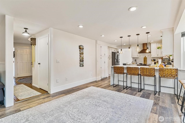 7707 42nd Ave E, Tacoma, WA 98443 - kitchen featuring custom range hood, a peninsula, stainless steel fridge with ice dispenser, wood finished floors, and white cabinetry