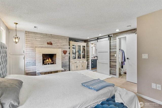 7707 42nd Ave E, Tacoma, WA 98443 - bedroom featuring a barn door, light colored carpet, a textured ceiling, a spacious closet, and a brick fireplace