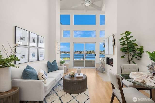 2400 8th Ave N Unit 2, Seattle, WA 98109 - living room with wood finished floors, a glass covered fireplace, a ceiling fan, a towering ceiling, and a water view