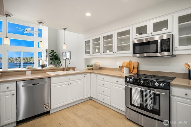 2400 8th Ave N Unit 2, Seattle, WA 98109 - kitchen with stainless steel appliances, white cabinets, light wood-type flooring, hanging light fixtures, and recessed lighting