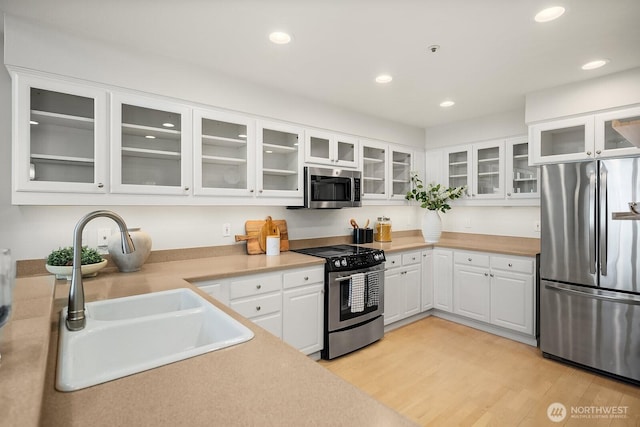 2400 8th Ave N Unit 2, Seattle, WA 98109 - kitchen featuring stainless steel appliances, light countertops, recessed lighting, glass insert cabinets, and white cabinetry