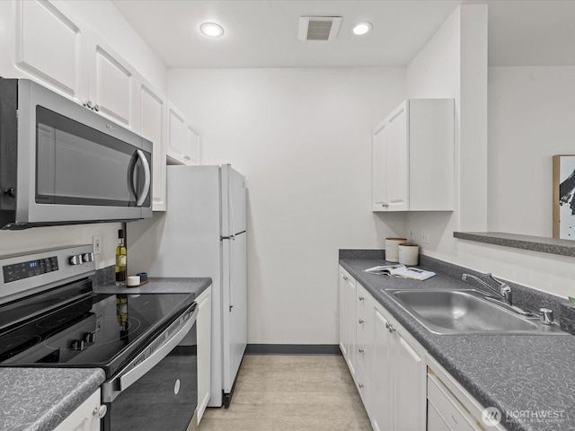 2415 2nd Ave Unit 541, Seattle, WA 98121 - kitchen featuring appliances with stainless steel finishes, white cabinets, light wood finished floors, dark countertops, and recessed lighting