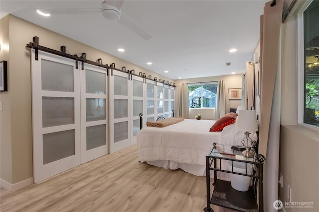6808 243rd Ave E, Buckley, WA 98321 - bedroom featuring a barn door, light wood-style flooring, and recessed lighting
