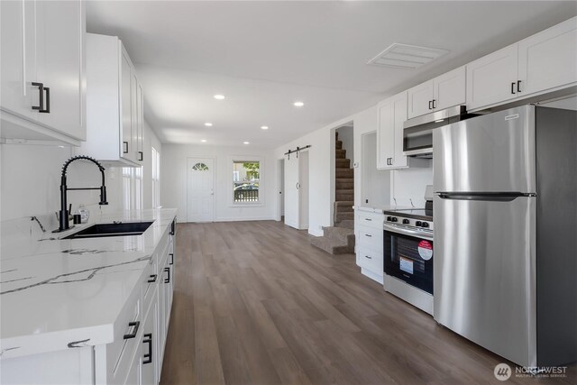 1433 E 32nd St, Tacoma, WA 98404 - kitchen featuring stainless steel appliances, light stone countertops, recessed lighting, wood finished floors, and white cabinetry