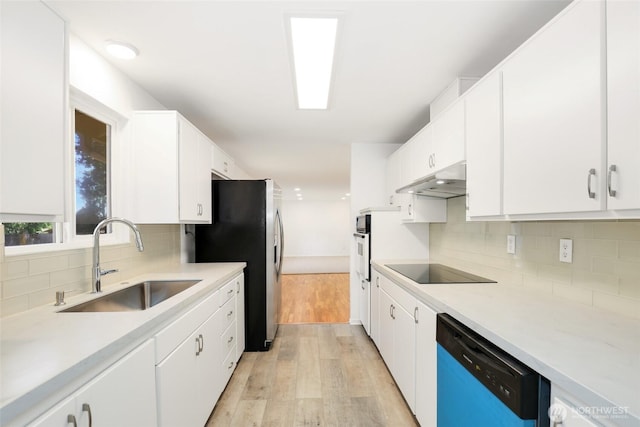 16548 115th Ave SE, Renton, WA 98055 - kitchen with dishwashing machine, black electric stovetop, under cabinet range hood, light wood-style floors, and decorative backsplash