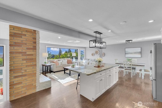 619 8th Ave S, Edmonds, WA 98020 - kitchen with freestanding refrigerator, dark wood finished floors, white cabinets, a breakfast bar area, and light stone countertops