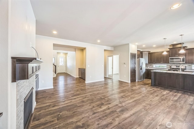 4749 NE Waxwing Ct, Lacey, WA 98516 - kitchen with appliances with stainless steel finishes, dark brown cabinetry, a fireplace, light countertops, and dark wood-style flooring