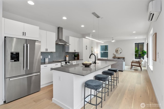 1327 N 185th St Unit A, Shoreline, WA 98133 - kitchen featuring appliances with stainless steel finishes, wall chimney exhaust hood, a wall mounted AC, light wood-style floors, and a breakfast bar