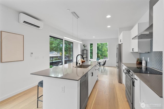 1327 N 185th St Unit A, Shoreline, WA 98133 - kitchen featuring an AC wall unit, appliances with stainless steel finishes, wall chimney exhaust hood, light wood-style floors, and recessed lighting