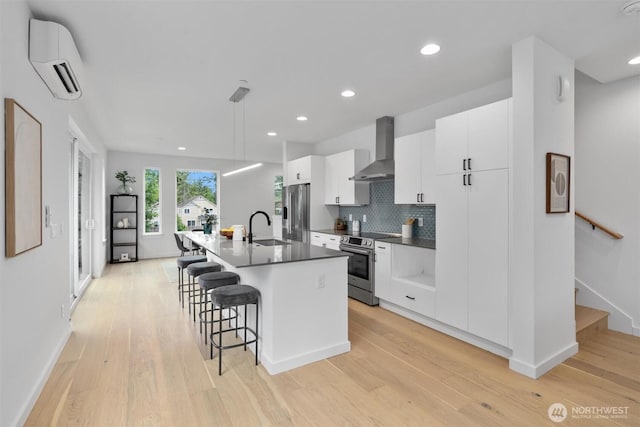 1327 N 185th St Unit A, Shoreline, WA 98133 - kitchen featuring wall chimney range hood, stainless steel appliances, a wall mounted AC, a breakfast bar area, and a center island with sink